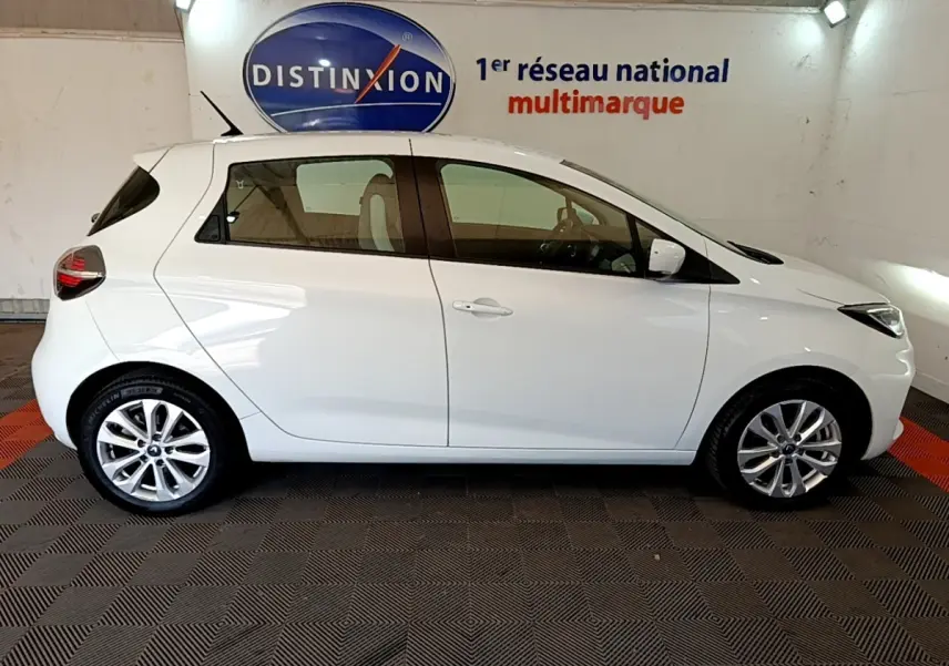 Profil latéral droit d'une Renault ZOE Zen R110 blanche de 2019, compacte et électrique, dans un showroom intérieur.