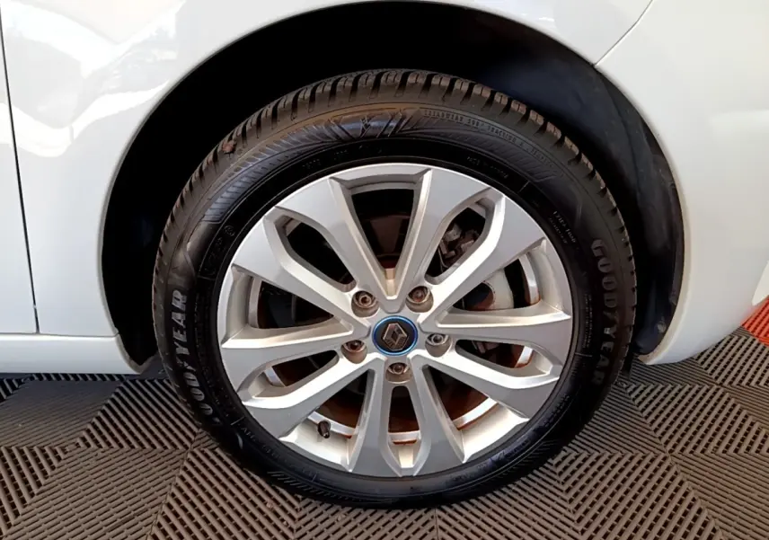 Gros plan sur la roue avant droite d'une Renault ZOE blanche, jante alliage argent avec logo Renault au centre.