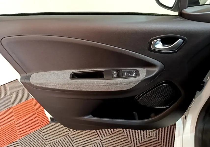 Vue intérieure de la porte avant gauche de la Renault ZOE blanche, avec panneau noir et insert tissu gris.