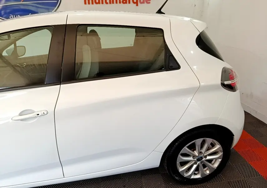 Vue latérale droite d'une Renault ZOE blanche 2019 avec jante alliage et vitres teintées arrière.