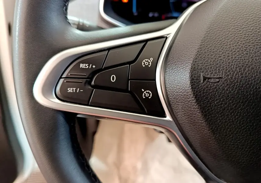 Gros plan sur les commandes de régulateur de vitesse au volant cuir noir de la Renault ZOE blanche.