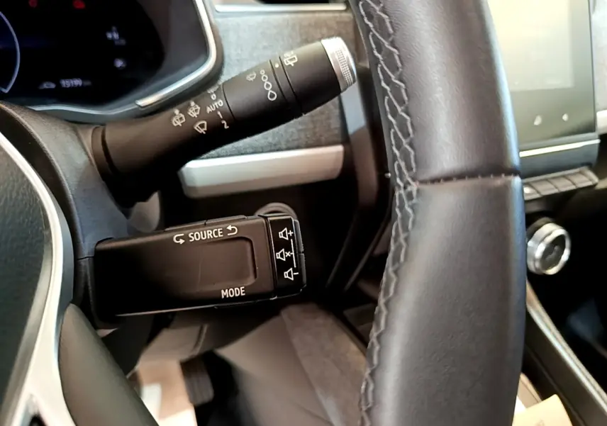 Gros plan sur le volant cuir noir et les commandes au volant du tableau de bord de la Renault ZOE blanche 2019.