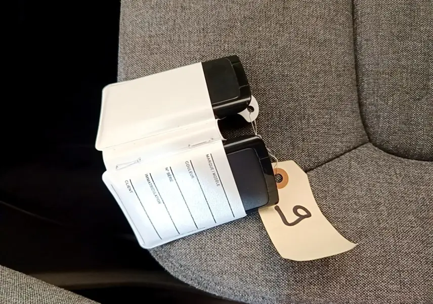 Clé carte Renault ZOE blanche posée sur un siège gris, avec étiquette numérotée attachée.