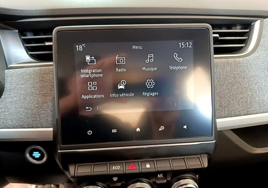 Écran tactile central de la Renault ZOE blanche 2019, affichant le menu multimédia avec commandes sous l'écran.