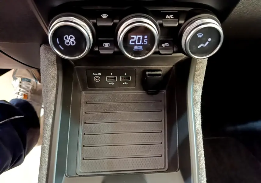 Vue rapprochée du tableau de bord central de la Renault ZOE Zen R110 blanc, montrant les commandes de climatisation et la zone de recharge par induction.