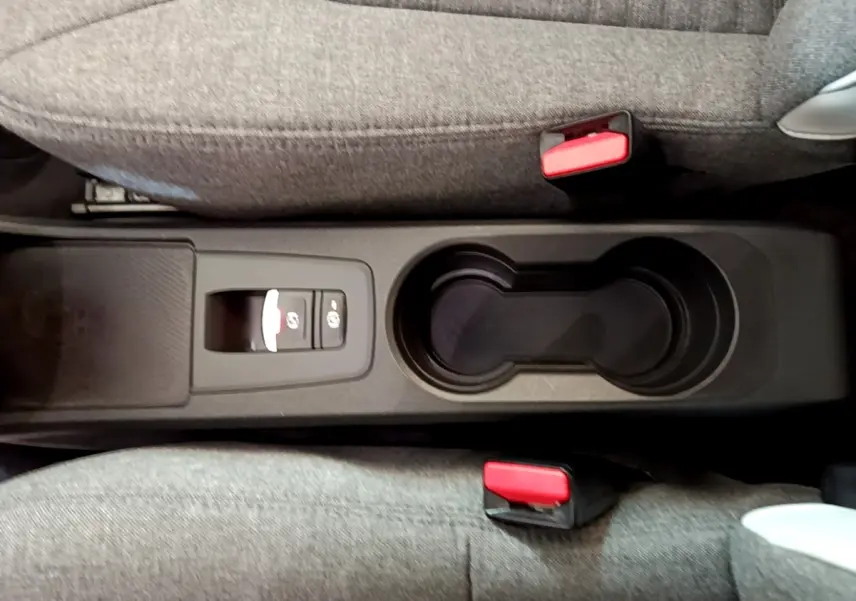 Vue plongeante sur la console centrale noire avec porte-gobelets et bouton frein à main électrique de la Renault ZOE blanche.