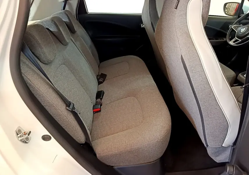 Vue intérieure côté arrière gauche de la Renault ZOE blanche, sièges tissu gris et détails intérieurs modernes.