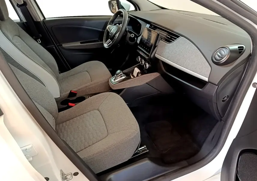 Intérieur avant droit de la Renault ZOE blanche, sièges tissu gris, tableau de bord avec écran tactile central.