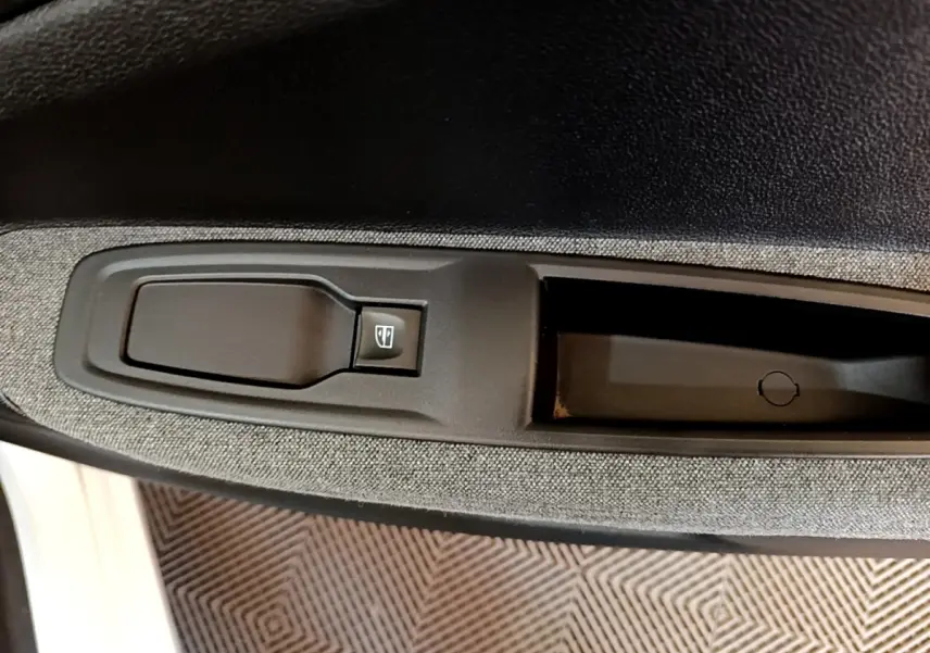 Gros plan sur la commande de lève-vitre côté conducteur de la Renault ZOE Zen R110 blanc, tissu gris sur la portière.