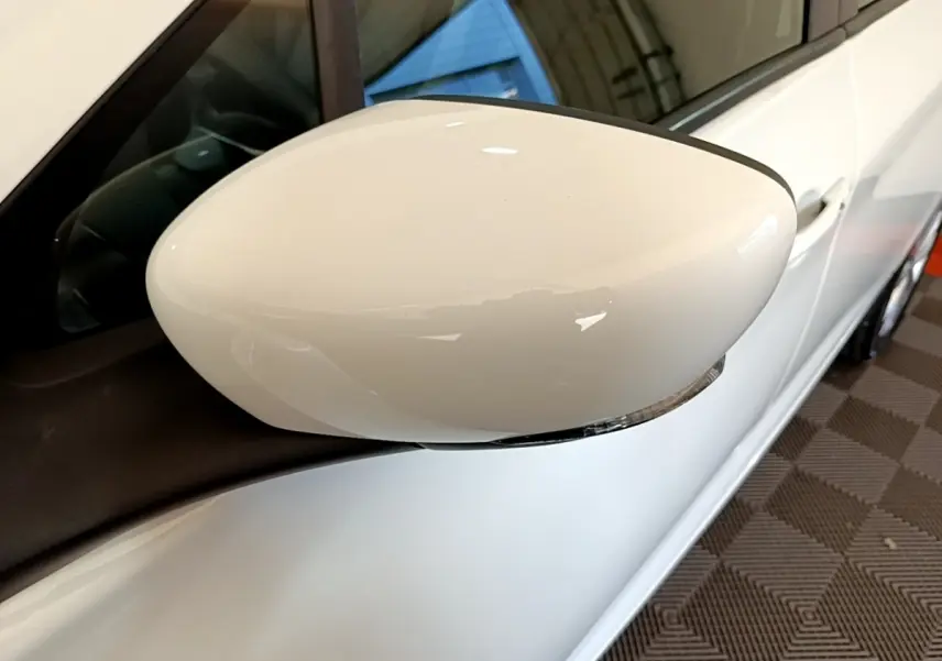 Rétroviseur blanc côté gauche d’une Renault ZOE Zen R110 2019, vue rapprochée sur la portière et la vitre.