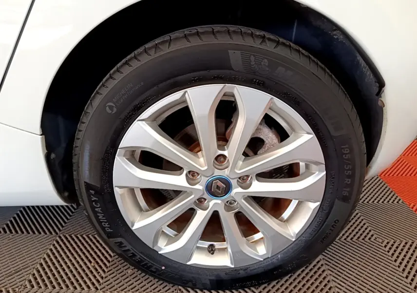 Gros plan sur la roue avant gauche blanche d'une Renault ZOE 2019 avec jante alliage et logo Renault central.