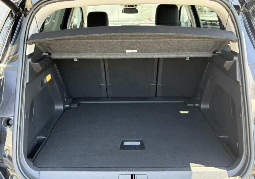 Coffre ouvert vu de l'arrière du Citroën C5 Aircross Hybrid noir Perla, avec cache-bagages relevé et espace de rangement visible.