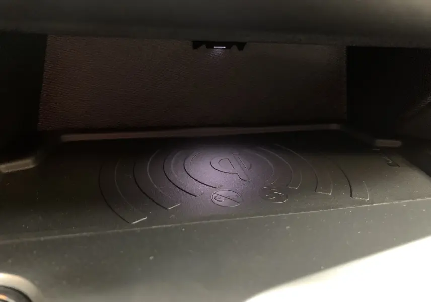 Gros plan sur le chargeur à induction Qi intégré dans la console centrale de la Peugeot 308 GT PHEV 180 blanc nacré.