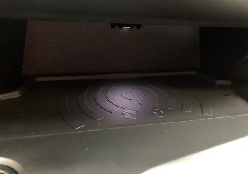 Gros plan sur le chargeur sans fil Qi intégré dans la console centrale de la Peugeot 308 GT PHEV 2022.