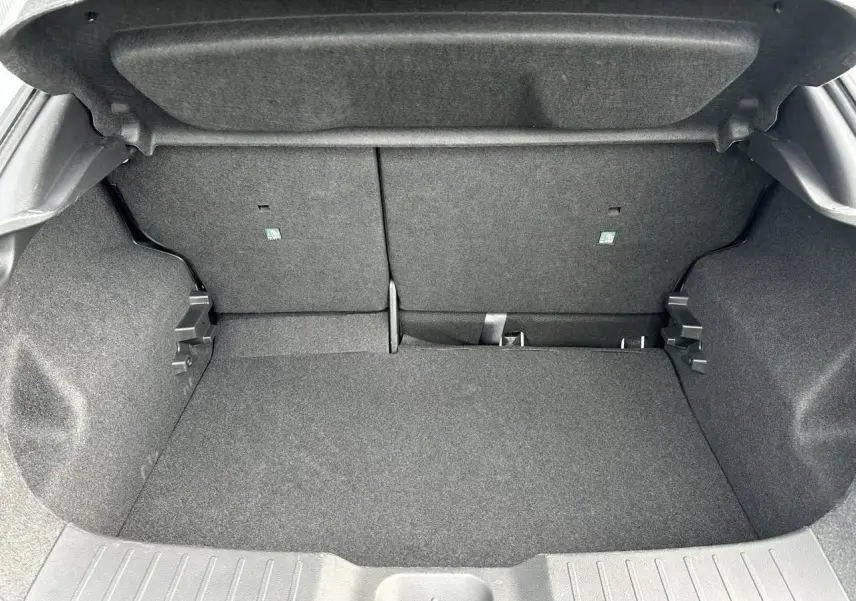 Coffre ouvert du Nissan Juke blanc nacré 2025, montrant l'espace de chargement et la banquette arrière rabattable.