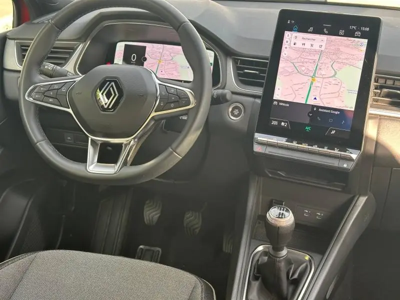 Vue intérieure du poste de conduite du Renault Captur 2025, volant multifonction et écran tactile central avec navigation visible.