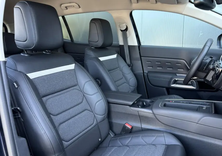 Vue intérieure côté avant droit du Citroën C5 Aircross Hybrid 2025, sièges Advanced Comfort en cuir et tissu gris foncé.