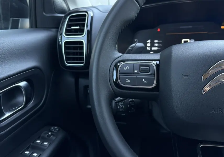 Détail du volant et tableau de bord noir du Citroën C5 Aircross Hybrid 2025, avec commandes intégrées au volant.