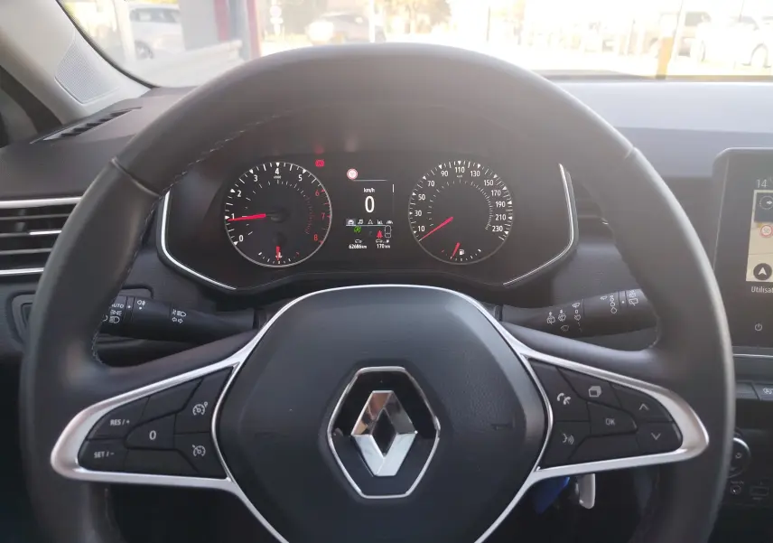 Vue centrée sur le volant noir de la Renault Clio blanche 2021, avec tableau de bord digital et commandes intégrées.