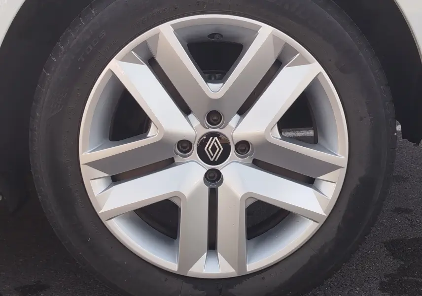 Gros plan sur la jante alliage argentée d’une Renault Clio blanche, mettant en valeur le logo Renault central.