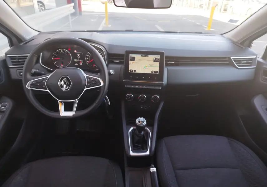 Vue intérieure frontale de la Renault Clio Business 2021 avec tableau de bord noir, écran tactile et levier de vitesse manuel.