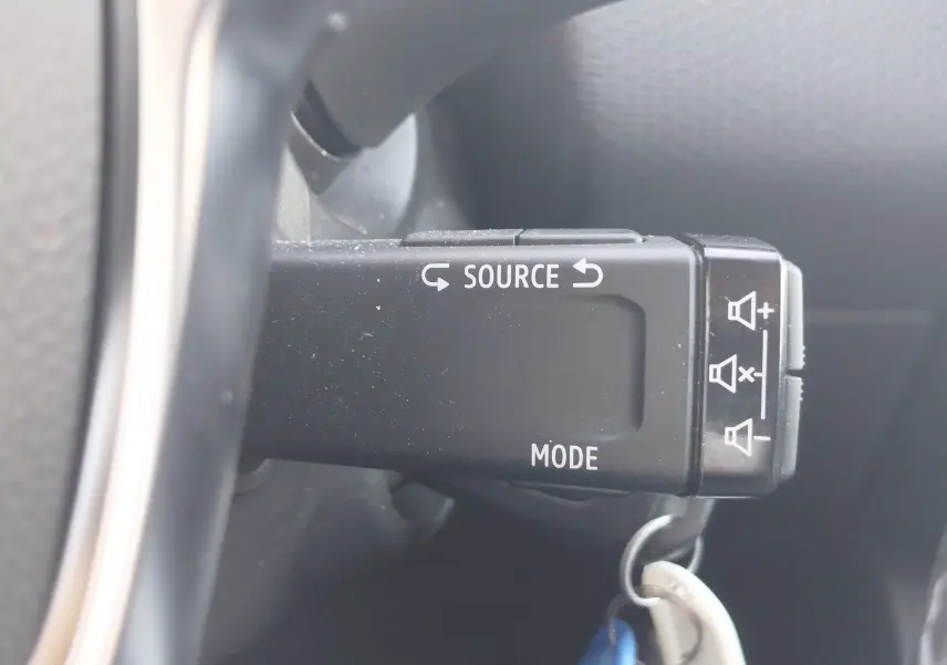 Gros plan sur la commande au volant noire de la Renault Clio blanche 2021, avec boutons source et mode visibles.