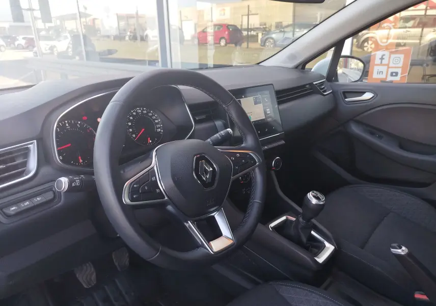 Vue intérieure du poste de conduite de la Renault Clio blanche 2021, avec volant multifonction et boîte manuelle visible.