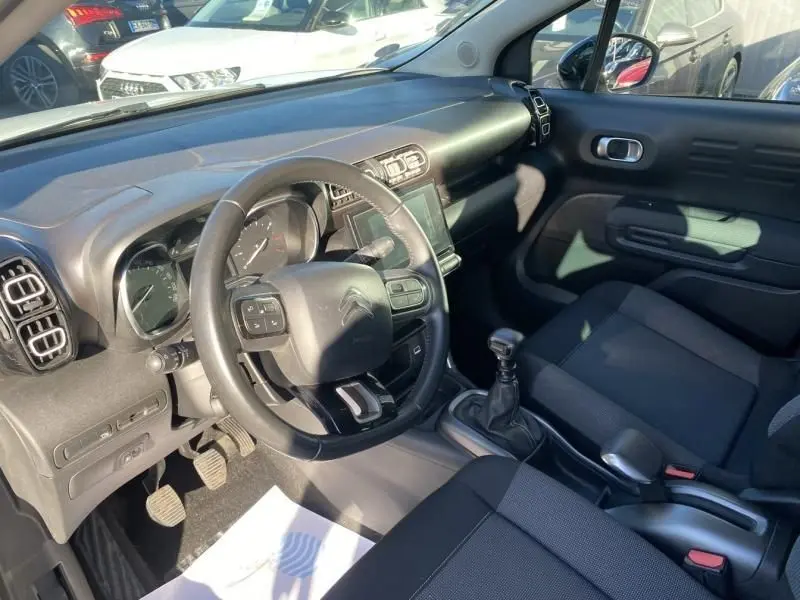 Vue intérieure côté conducteur du Citroën C3 Aircross blanc 2019, avec volant multifonction et boîte manuelle visible.