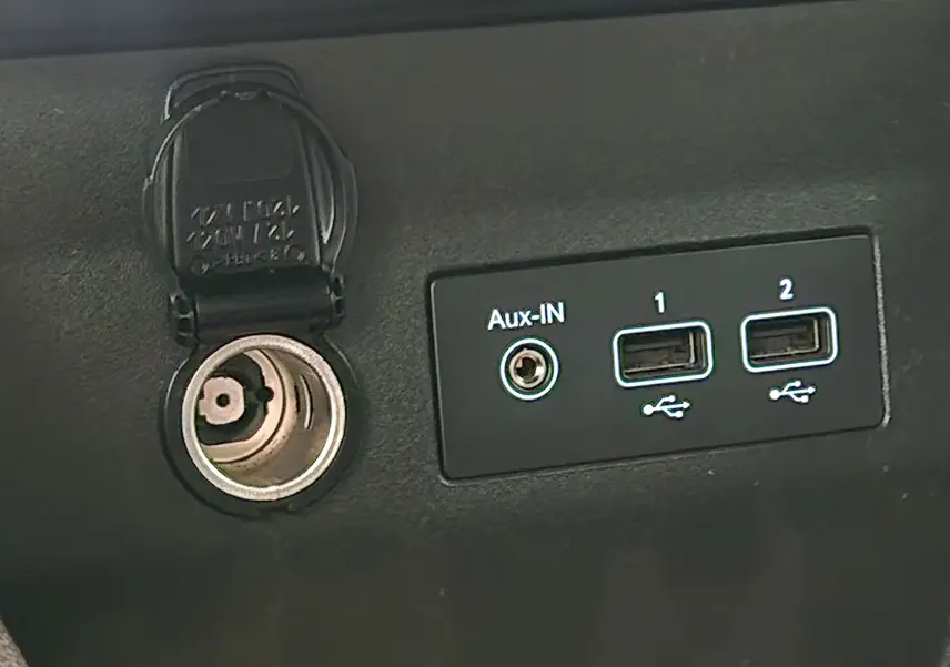 Prise allume-cigare et ports Aux-IN et USB en gros plan sur la console intérieure d'une Renault Clio V gris platine.