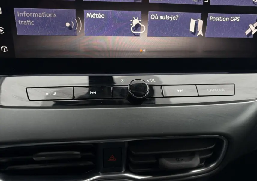 Gros plan sur la console centrale du Nissan Juke blanc nacré 2025, mettant en valeur les commandes multimédia et la ventilation.