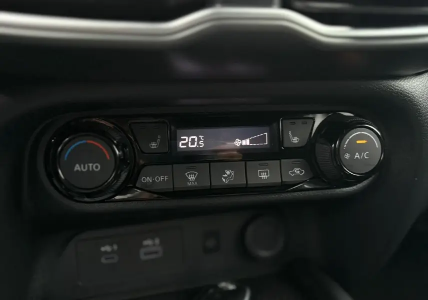 Gros plan sur la console de climatisation automatique du Nissan Juke blanc nacré, avec affichage digital et commandes tactiles.