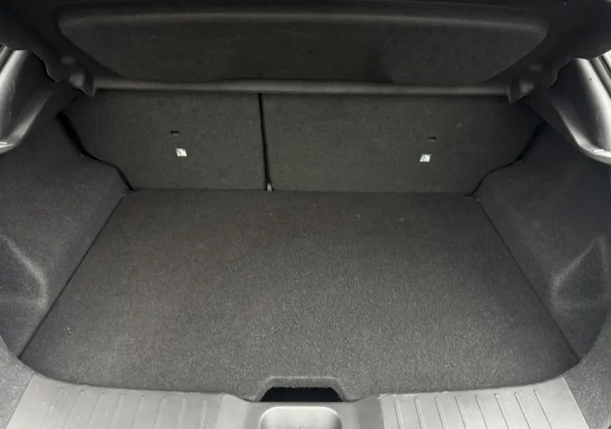 Coffre vide du Nissan Juke blanc nacré, vue intérieure arrière avec banquette rabattable et revêtement gris.