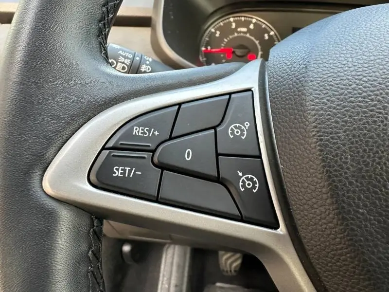 Gros plan sur les commandes de régulateur de vitesse au volant d'une Dacia Sandero 2025 couleur Kaki Lichen.