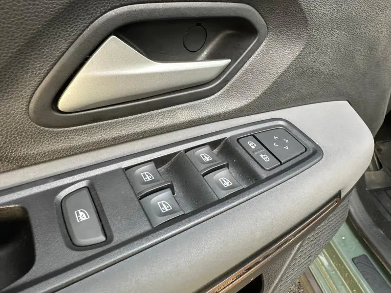 Gros plan sur les commandes de lève-vitres et rétroviseurs côté conducteur d'une Dacia Sandero 2025 kaki lichen.