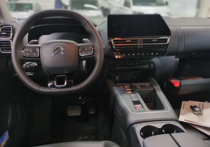 Intérieur noir du Citroën C5 Aircross Hybrid 2025, vue frontale sur volant, écran tactile et console centrale.