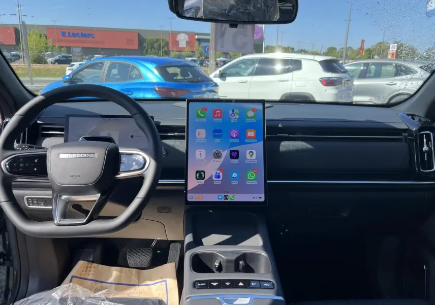 Vue intérieure avant du JAECOO J7 gris olive 2026, avec grand écran tactile vertical et volant multifonction.