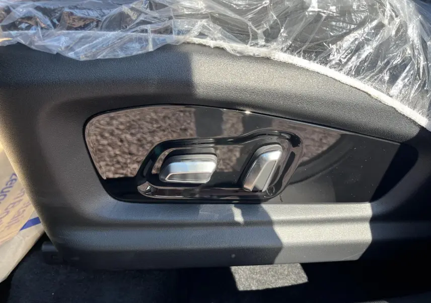 Gros plan sur les commandes de réglage électrique du siège côté conducteur du JAECOO J7 gris olive.