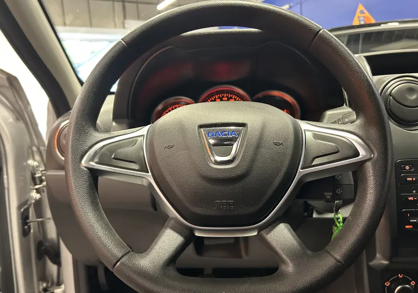 Volant noir avec logo Dacia au centre, vue frontale de l'intérieur du Dacia Duster gris 2017 avec tableau de bord visible.