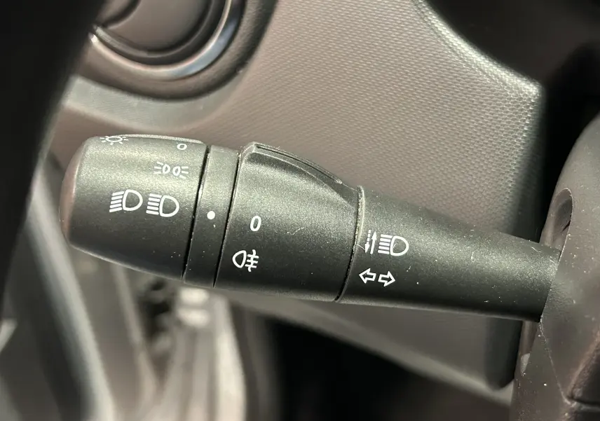 Gros plan sur la manette de commande des phares et clignotants du Dacia Duster gris 2017, intérieur côté gauche.