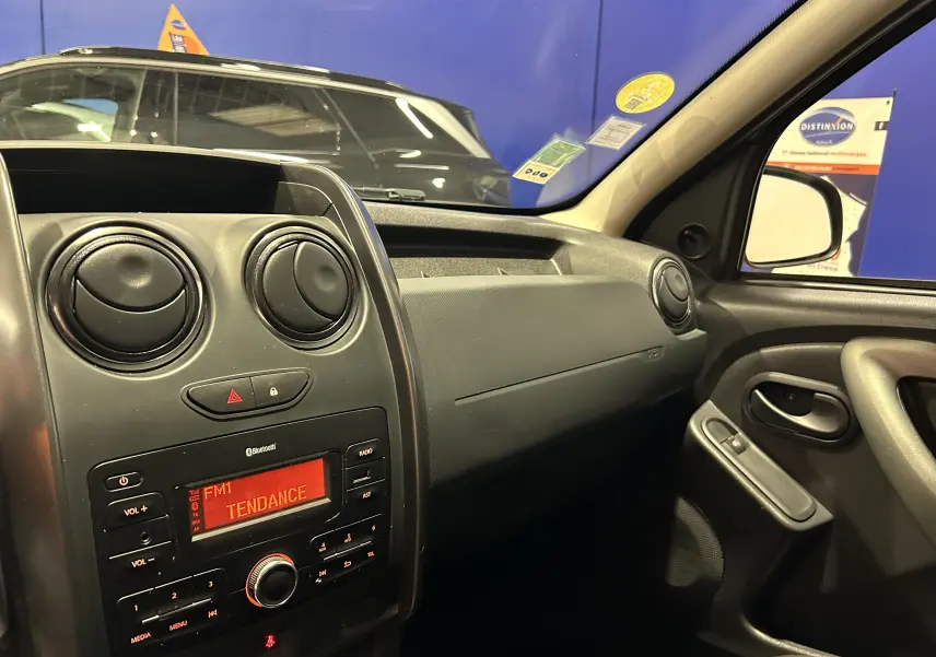 Intérieur du Dacia Duster 2017 gris, vue côté passager sur tableau de bord et console centrale avec radio allumée.