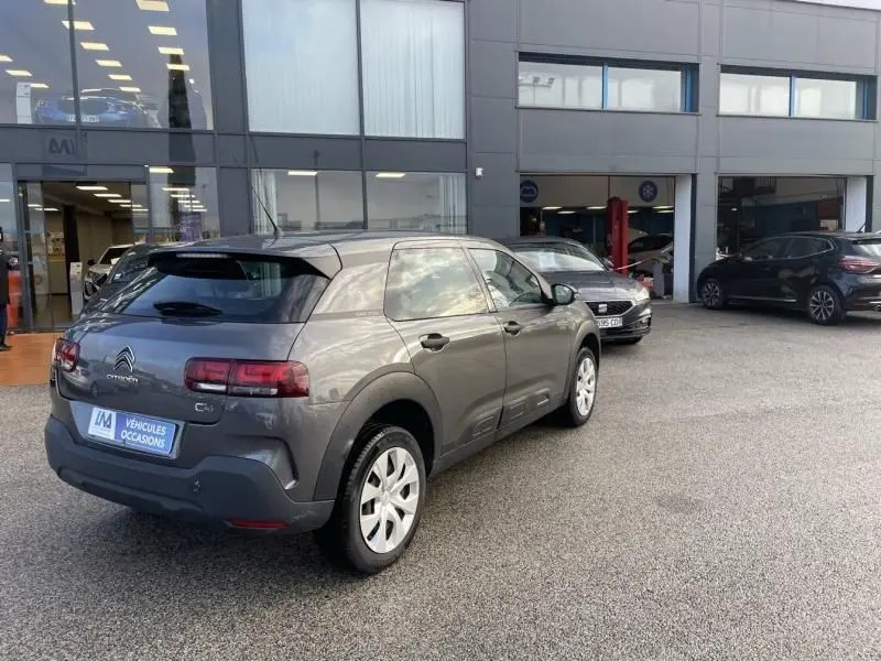 Citroën C4 Cactus gris foncé métal vue 3/4 arrière droit, avec ses feux arrière caractéristiques et ses protections latérales.