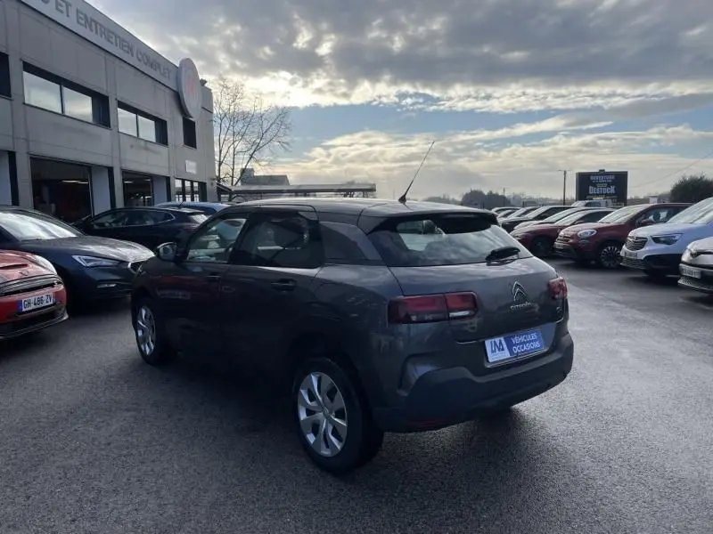 Citroën C4 Cactus gris foncé métal vue 3/4 arrière côté gauche, stationnée sur un parking extérieur.