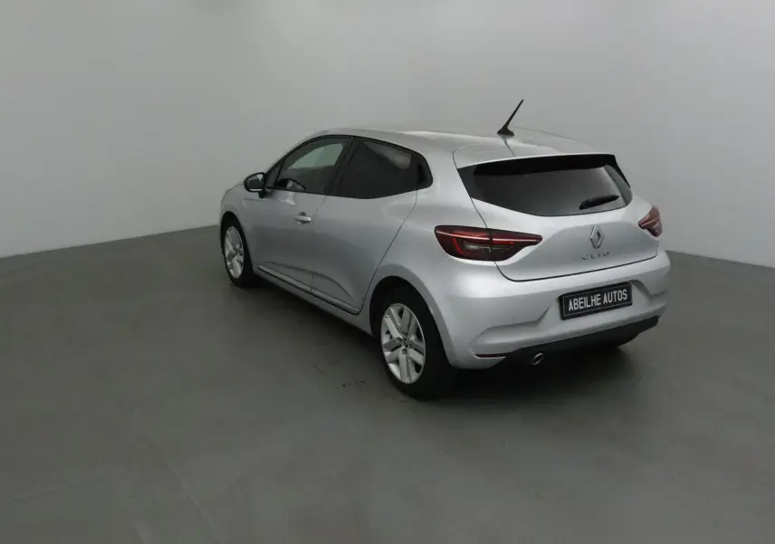 Renault Clio V gris platine vue 3/4 arrière droit dans un studio, avec vitres arrière teintées et plaque Abeilhe Autos.