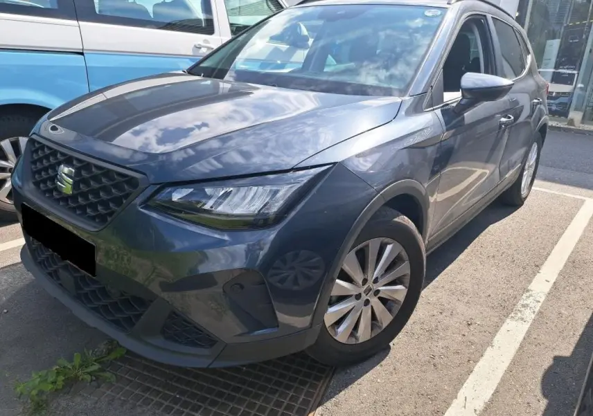 SEAT Arona gris magnétique vu en 3/4 avant droit, mettant en valeur ses phares EcoLED et sa calandre distinctive.