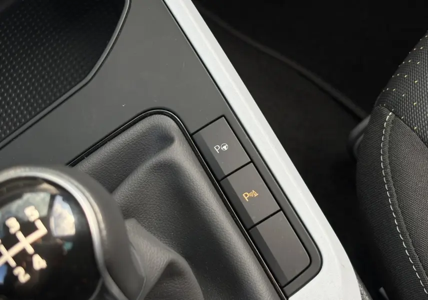 Gros plan sur la console centrale côté droit du SEAT Arona gris, avec levier de vitesse manuel et boutons d'aide au stationnement.