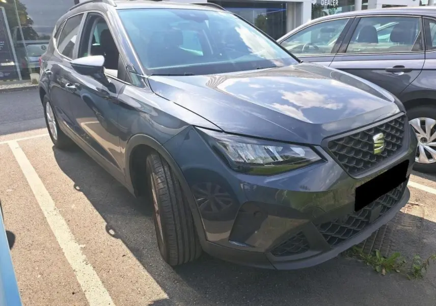 SEAT Arona gris magnétique vue 3/4 avant gauche, avec calandre noire et projecteurs EcoLED visibles.