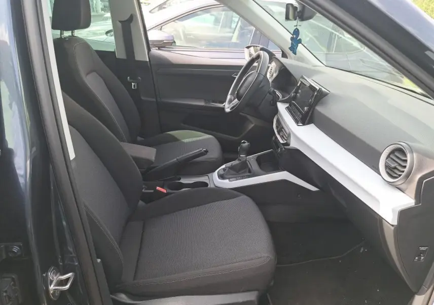 Intérieur avant droit du SEAT Arona gris Magnétique 2024, montrant sièges tissu, volant multifonction et écran tactile central.