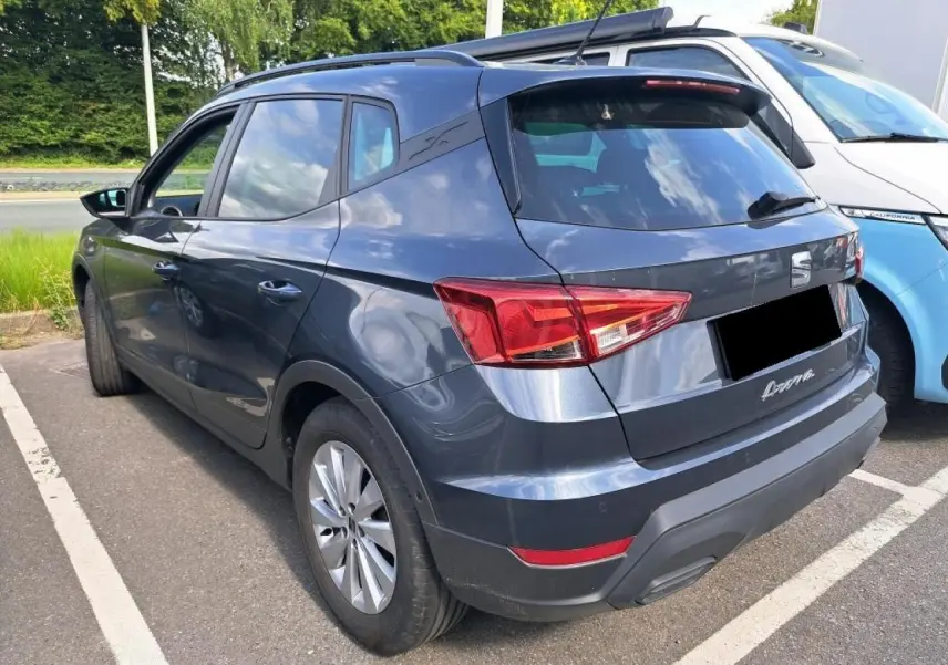Vue 3/4 arrière gauche d'un SEAT Arona gris magnétique garé, avec feux arrière et jantes alliage visibles.