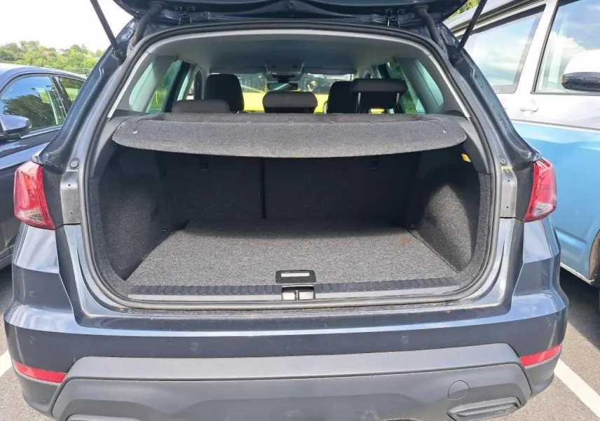 Vue arrière du coffre ouvert du SEAT Arona 2024 gris magnétique, montrant l'espace de chargement vide.