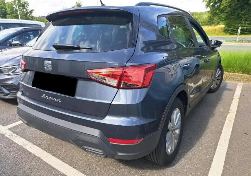 SEAT Arona gris magnétique vue 3/4 arrière droit, avec feux arrière et jantes alliage visibles sur parking.